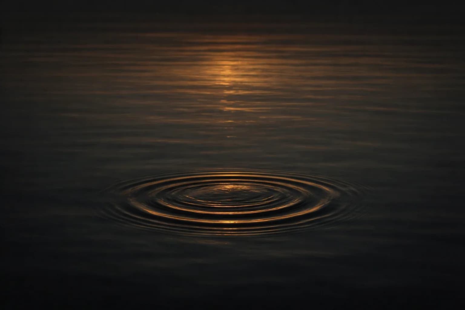 Onda expandiéndose en agua oscura y serena